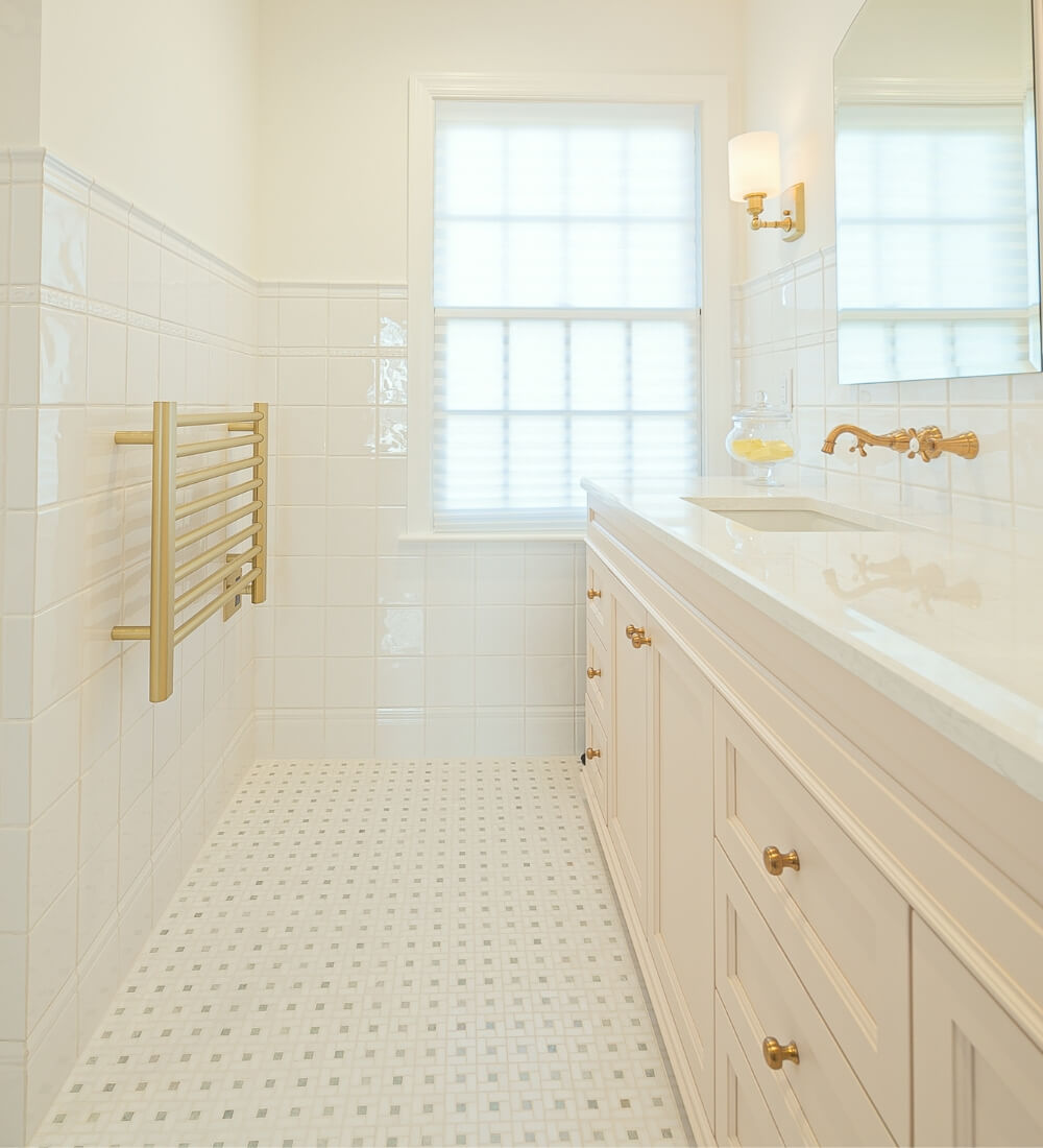 Spacious master bathroom featuring a double vanity with brass fixtures, white cabinetry, and bright natural light in a Rosemont, NJ remodel.