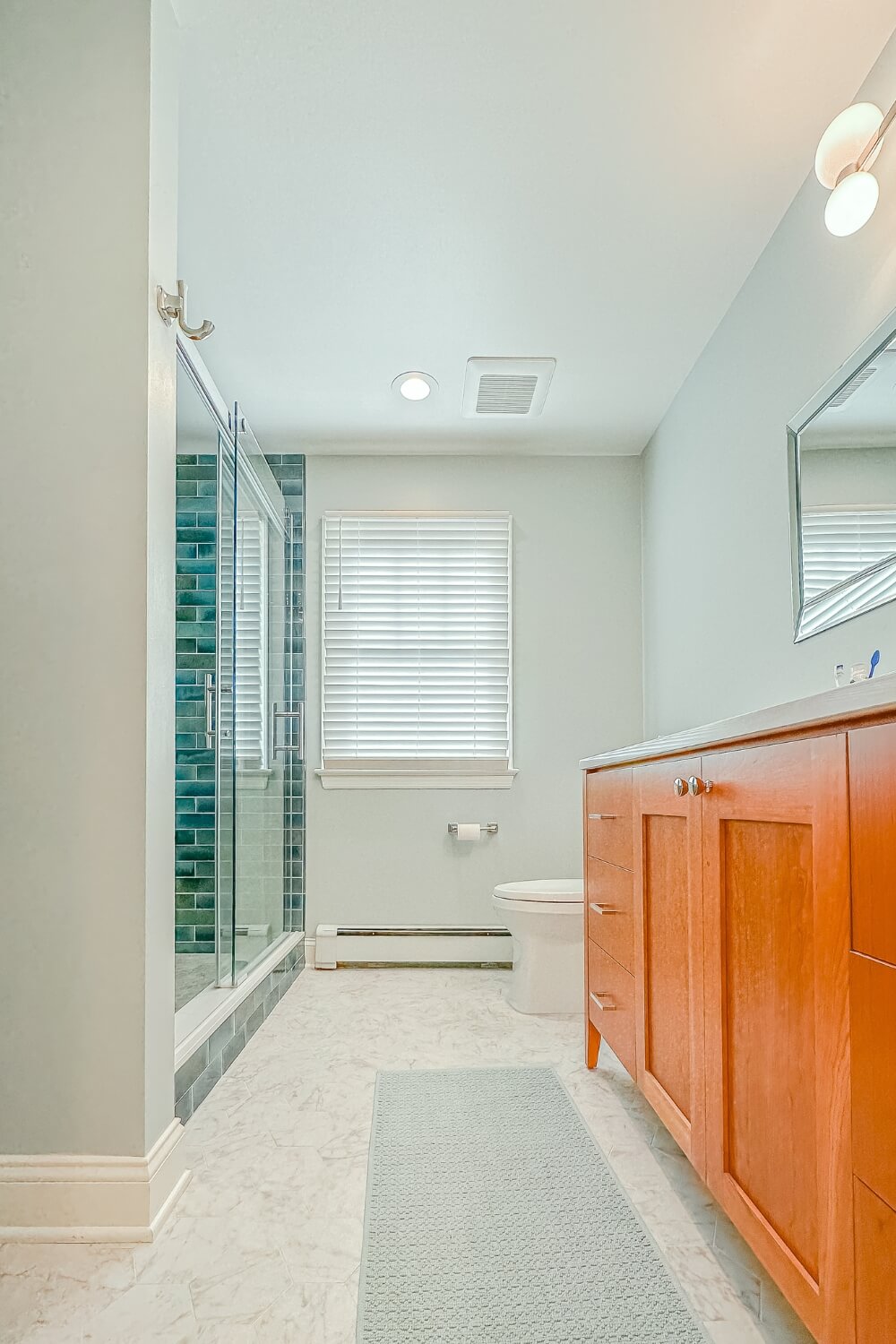 Spa-like bathroom remodel with cherry wood vanity, white countertops, and glass-enclosed shower in Rosemont, NJ