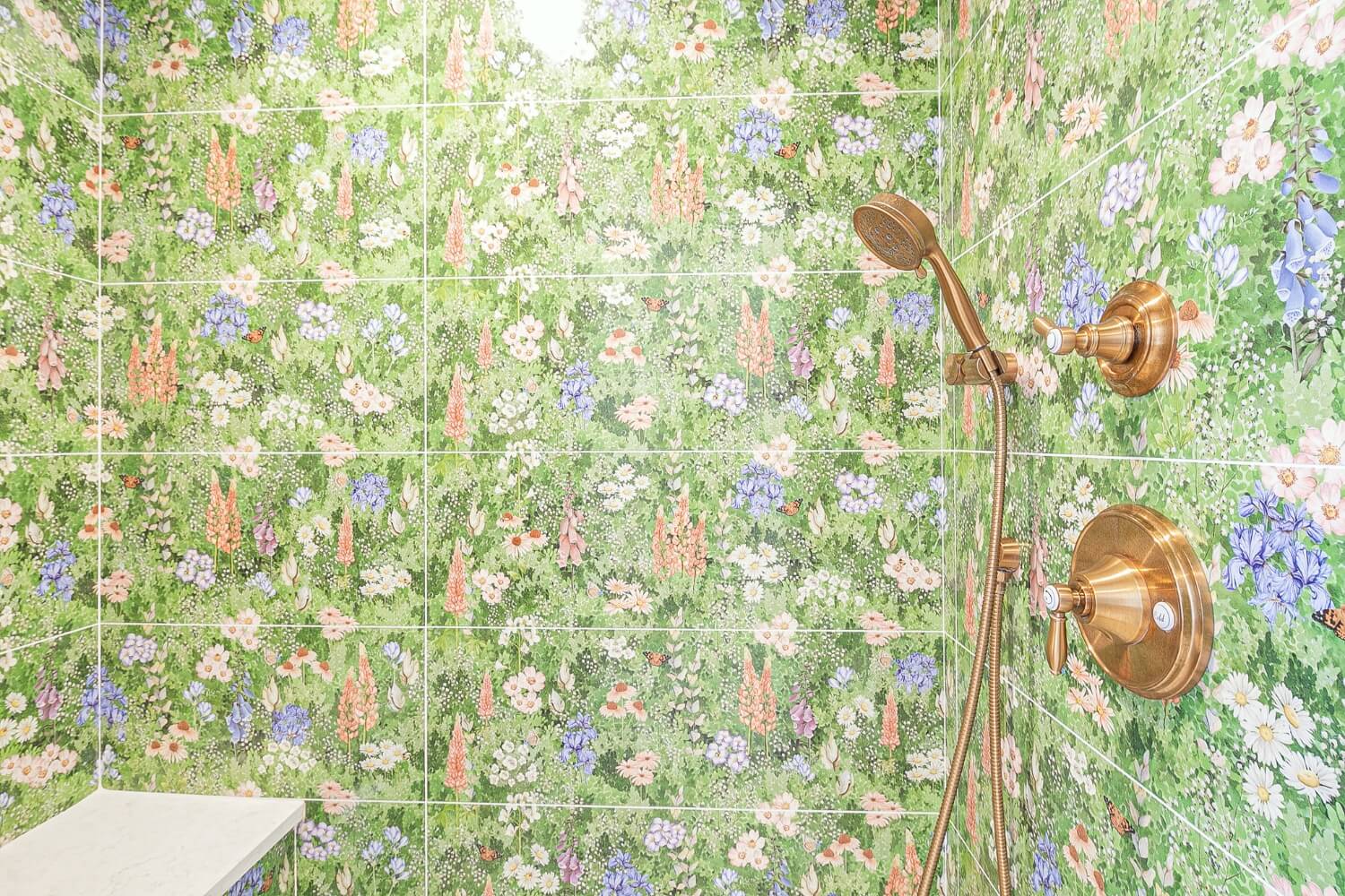 Close-up view of floral-themed shower tiles with elegant brass fixtures.