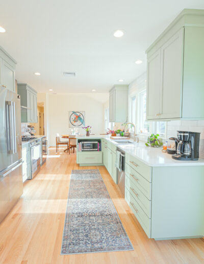 Green kitchen cabinetry with white quartz countertops and a modern open-concept design in Rosemont, NJ remodel.