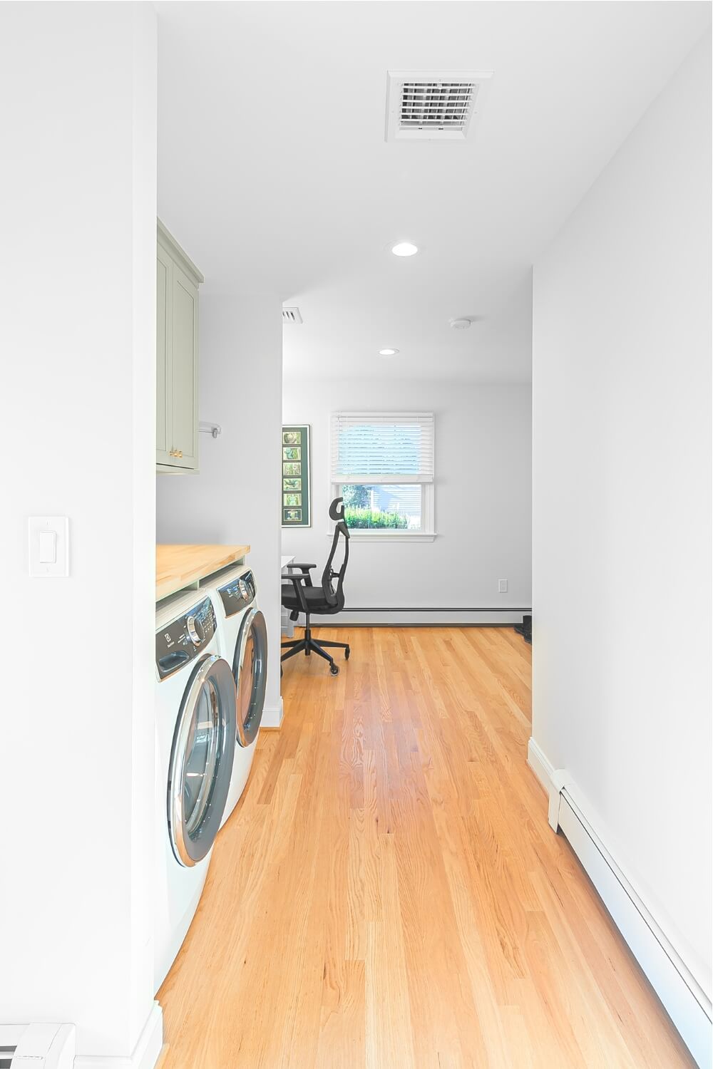 Laundry and office combo with white walls, sage green cabinets, and hardwood flooring in Rosemont remodel