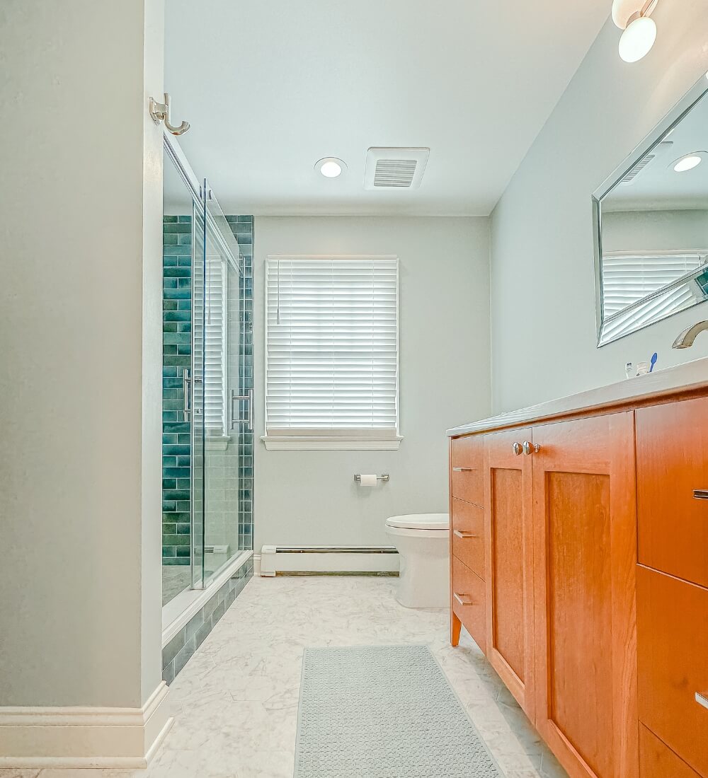 Luxurious bathroom remodel with walk-in glass shower, wooden vanity, and modern lighting in a master suite.