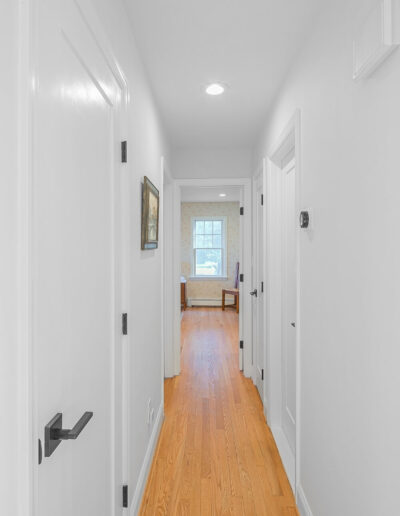 Hallway remodel with white doors, modern black hardware, and natural hardwood floors in Rosemont home