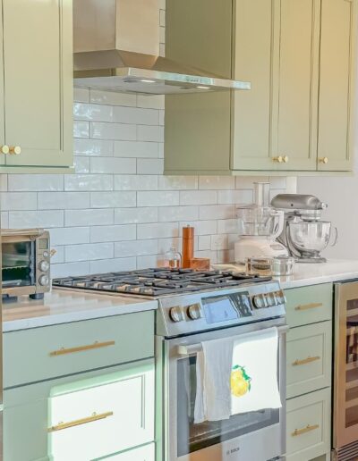 Modern kitchen design with sage green cabinets, subway tile backsplash, and stainless steel appliances