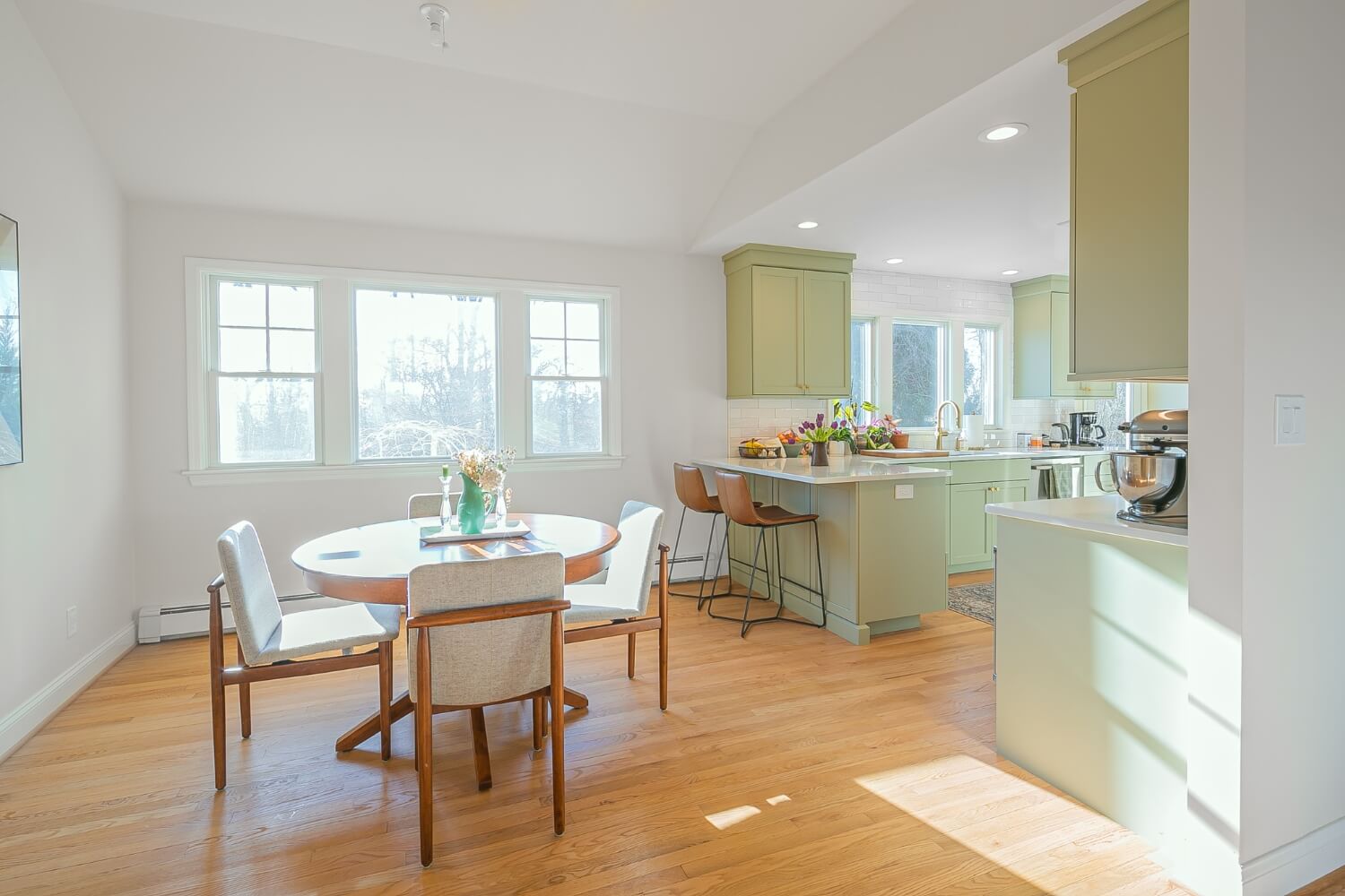 Open-concept kitchen and dining area with green cabinetry and bar seating, Rosemont, NJ remodel.