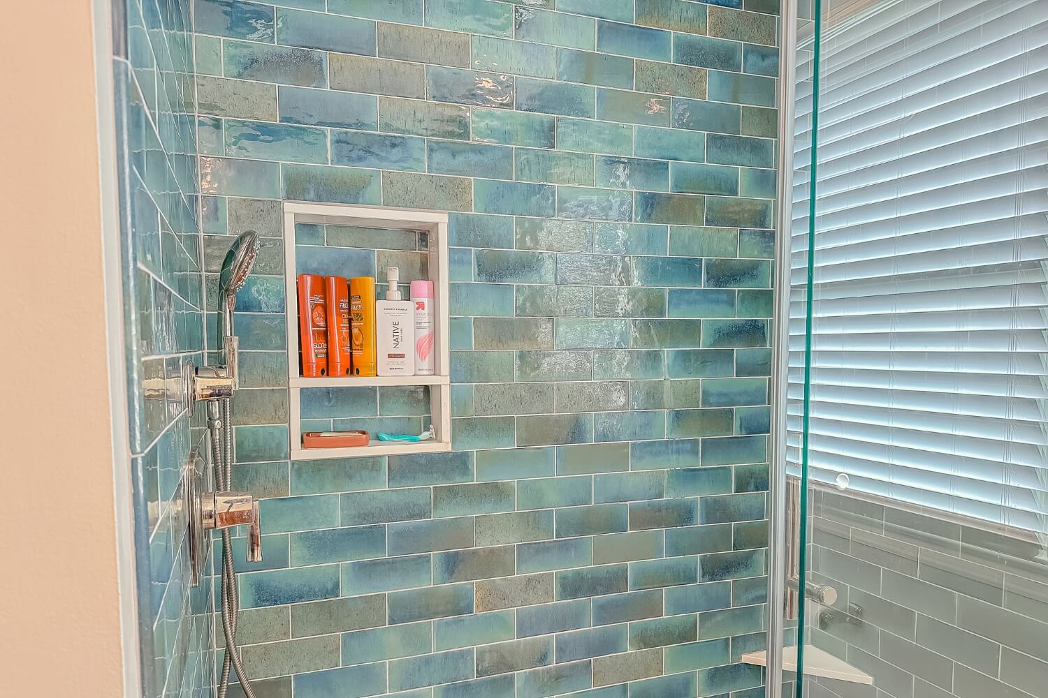 Shower with aqua glass tiles and recessed shelving in remodeled bathroom, Rosemont, NJ.