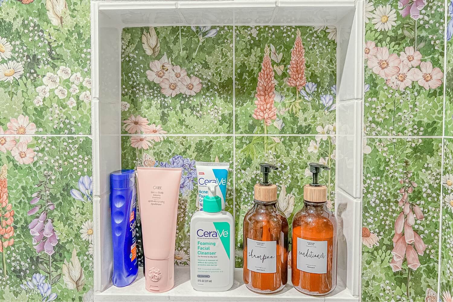 Shower niche featuring decorative bottles and grooming essentials, framed by colorful tiles.