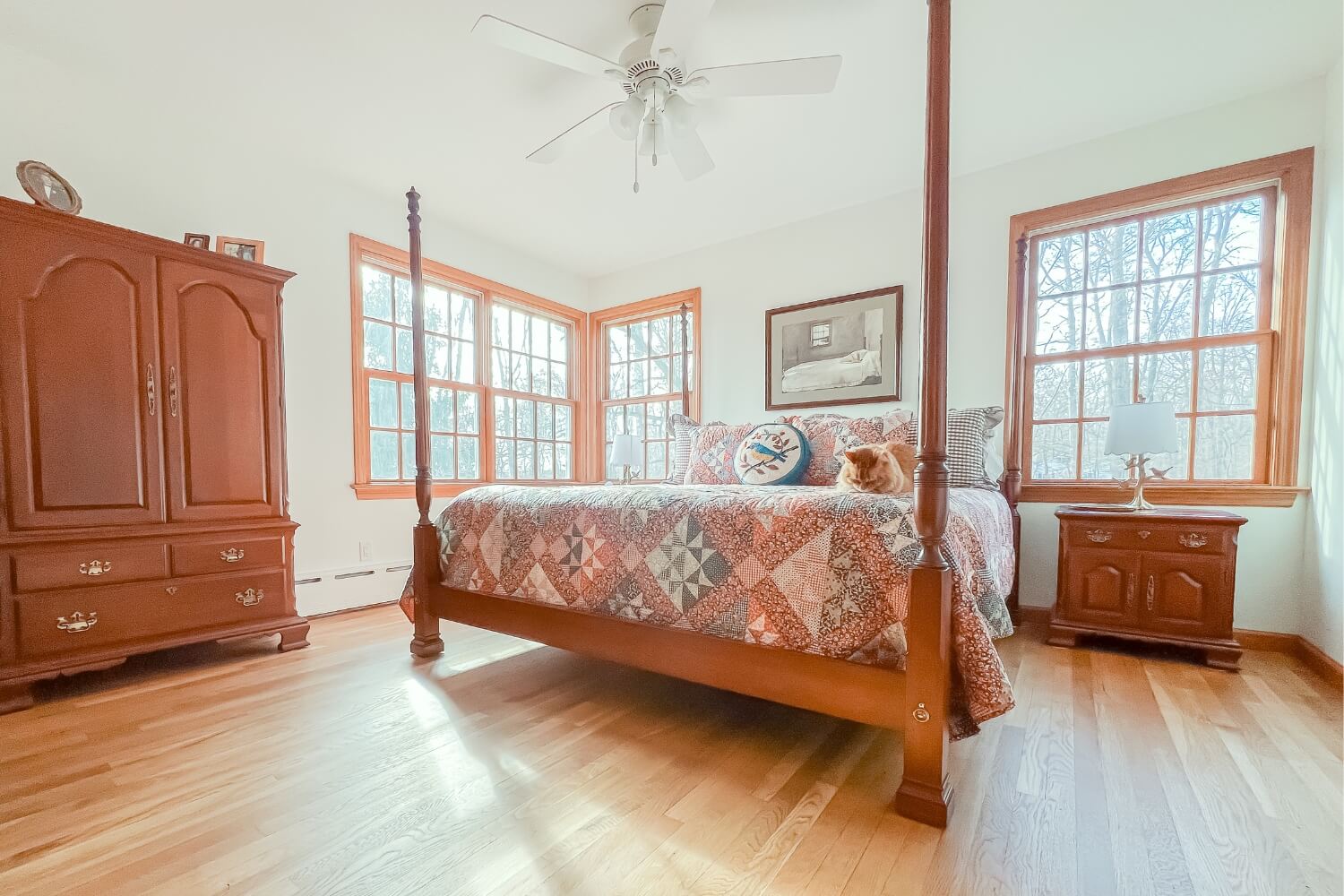 raditional bedroom with hardwood flooring, a four-poster bed, and a cat resting on the quilt.