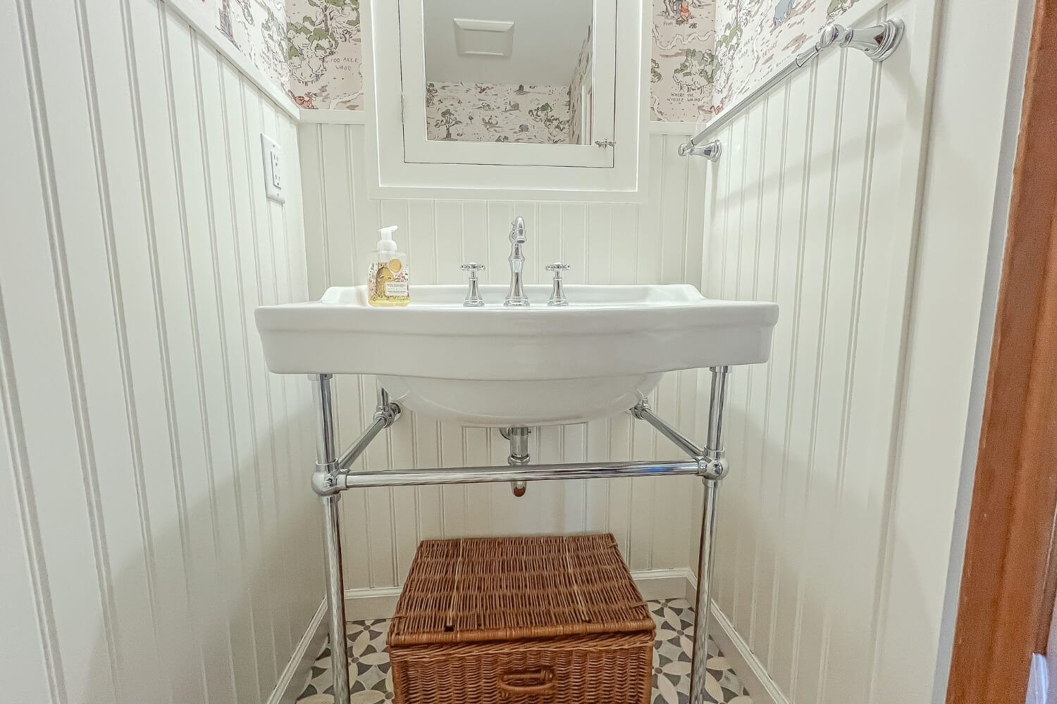 Vintage-inspired bathroom sink with chrome legs and a wicker basket below.