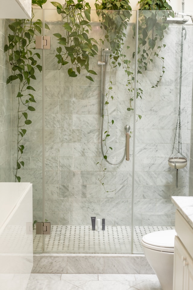 Luxurious glass shower with marble tile and hanging greenery for a spa-like feel.